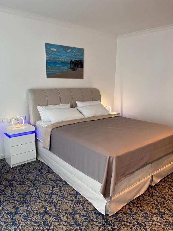 omfortables Kingsize-Bett im Zimmer „Rosengarten“ des Art Hotel House One, mit stilvollem Wandbild, eleganter Bettbeleuchtung und hochwertigem Teppichboden.